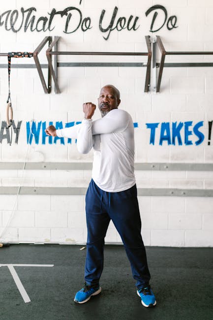 Senior man stretching arms in gym setting, promoting active lifestyle and fitness.